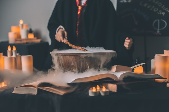 شخصی با ردای Harry Potter که چوب‌دستی را بالای کاسه‌ای مه‌آلود تکان می‌دهد